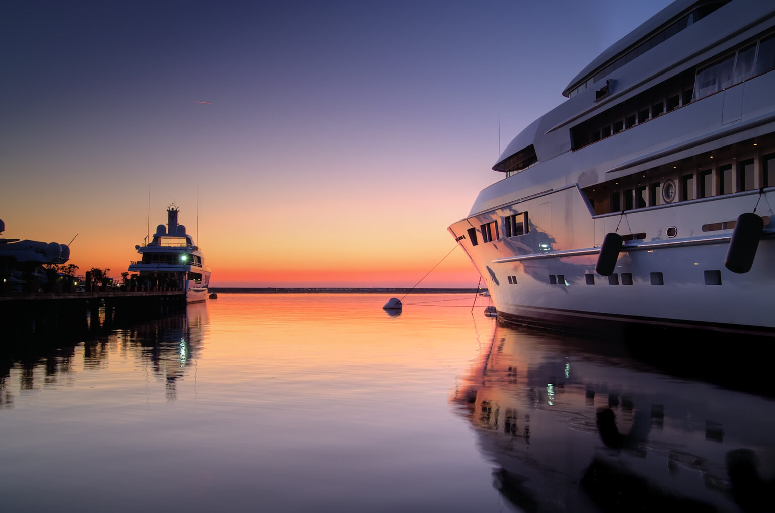 Ocean sunset with two superyachts
